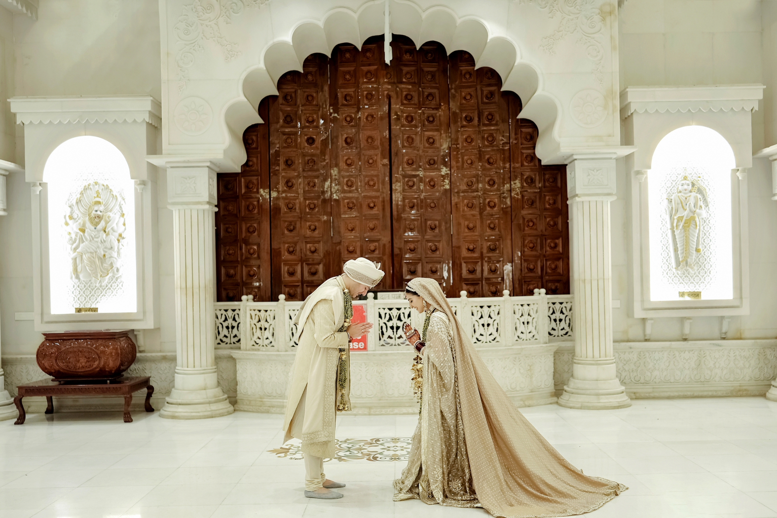Couple in traditional namastey pose after their varmala in temple wedding in Iskon Ludhiana