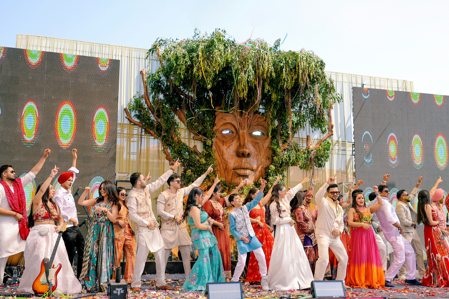 Guests and family members dancing together on stage at a vibrant Indian wedding celebration, surrounded by colourful outfits and festive décor.